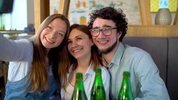 Young friends sit in a cafe, drink coffee and have fun communicating. Slow motion video