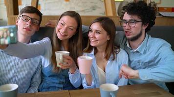 Young friends sit in a cafe, drink coffee and have fun communicating. Slow motion video