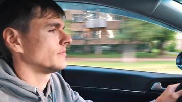 Young man driving a car down the street in sunny weather video