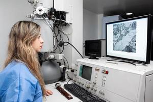 joven hembra científico trabajando a el laboratorio con un electrón microscopio foto