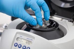 Closeup of a scientist hand placing a tube into an small table centrifuge. Spin column-based nucleic acid purification technique. photo