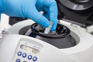 Closeup of a scientist hand placing a tube into an small table centrifuge. Spin column-based nucleic acid purification technique. photo