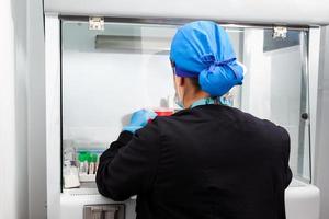 Young female scientist working in a safety laminar air flow cabinet at the laboratory photo