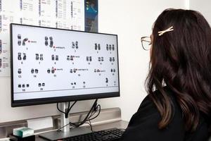 Computer screen showing a human karyotype. Young female scientist making a karyotype in the laboratory photo