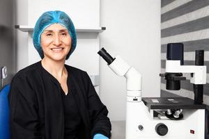 Female scientist looking at slides with patient samples using an inverted microscope in the laboratory. photo