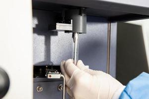 Scientist loading a test tube containing a patient sample on the  flow cytometer for analysis. Flow cytometer photo