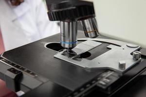 Scientist looking at liquid based cytology pap smear samples through a microscope. Medical analysis concept. Cervical cancer concept. photo