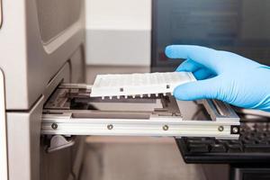 Scientist loading samples to a RT-PCR thermal cycler at the laboratory. Real-time polymerase chain reaction technique. RT-PCR technique photo