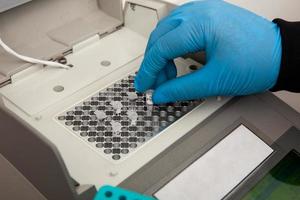 Closeup of a scientist hand while working at the laboratory with a thermal cycler. Polymerase chain reaction technique. PCR technique photo