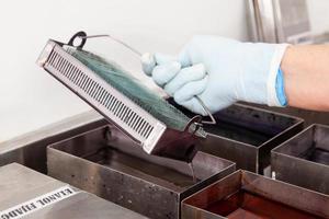 Scientist staining microscope slides for cytology studies in the laboratory. Fixation of samples through ethanol bathing. photo