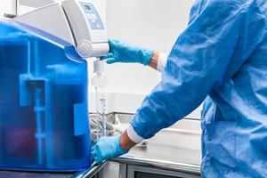 Scientist filling a graduated cylinder with distilled water at laboratory photo