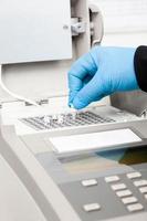 Closeup of a scientist hand while working at the laboratory with a thermal cycler. Polymerase chain reaction technique. PCR technique photo