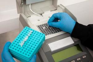 Closeup of a scientist hand while working at the laboratory with a thermal cycler. Polymerase chain reaction technique. PCR technique photo