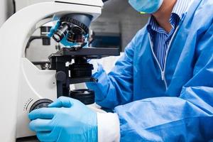 Young male scientist looking at slides under the microscope photo