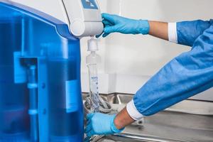Scientist filling a graduated cylinder with distilled water at laboratory photo