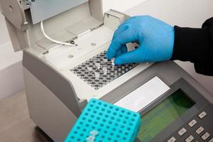 Closeup of a scientist hand while working at the laboratory with a thermal cycler. Polymerase chain reaction technique. PCR technique photo