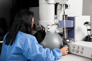 Young female scientist working at the laboratory with an electron microscope photo