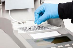 Closeup of a scientist hand while working at the laboratory with a thermal cycler. Polymerase chain reaction technique. PCR technique photo