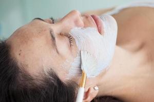 Facial mask application on young female patient photo