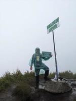 Man reach peak of mountain when rainy day with foggy vibes. The photo is suitable to use for adventure content media, nature poster and forest background.