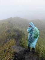 Man reach peak of mountain when rainy day with foggy vibes. The photo is suitable to use for adventure content media, nature poster and forest background.