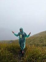 Man reach peak of mountain when rainy day with foggy vibes. The photo is suitable to use for adventure content media, nature poster and forest background.