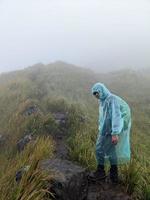 Man reach peak of mountain when rainy day with foggy vibes. The photo is suitable to use for adventure content media, nature poster and forest background.