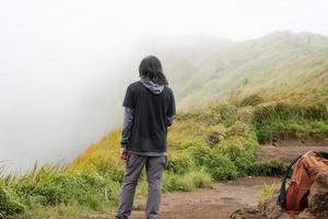 hombre excursionismo a el parte superior montaña, con savana pista y nublado vibras. el foto es adecuado a utilizar para aventuras contenido medios de comunicación, naturaleza póster y bosque antecedentes.