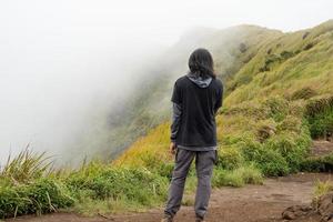 hombre excursionismo a el parte superior montaña, con savana pista y nublado vibras. el foto es adecuado a utilizar para aventuras contenido medios de comunicación, naturaleza póster y bosque antecedentes.