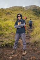 Man hiking to the top mountain, with Savana track and cloudy vibes. The photo is suitable to use for adventure content media, nature poster and forest background.