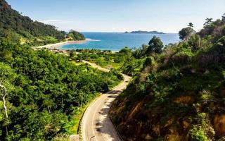 Aerial shot of coastal landscape with sea, road and hills photo