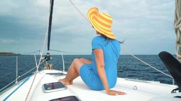 Woman in a yellow hat and blue dress girl rests aboard a yacht near the lighthouse on summer season at ocean video