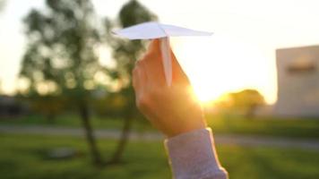 mujer lanza papel avión en contra puesta de sol antecedentes. concepto de falto a Vamos en vacaciones o viaje video