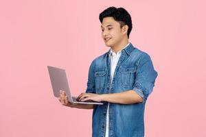 hermoso asiático hombre en azul camisa es utilizando ordenador portátil aislado en antecedentes. foto