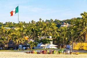 Puerto Escondido Oaxaca 2023 Palms parasols sun loungers beach people Zicatela Puerto Escondido Mexico. photo