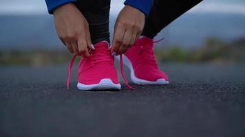 fonctionnement des chaussures - femme attacher chaussure lacets sur une désert route dans une montagneux zone video