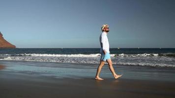 Happy man runs along the ocean beach at sunset. Concept of carefree modern life. Tenerife, Canarian Islands. Slow motion video