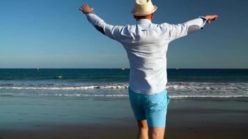 gelukkig Mens loopt langs de oceaan strand Bij zonsondergang. concept van zorgeloos modern leven. tenerife, Canarisch eilanden. langzaam beweging video