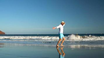gelukkig Mens loopt langs de oceaan strand Bij zonsondergang. concept van zorgeloos modern leven. tenerife, Canarisch eilanden. langzaam beweging video
