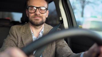 Satisfied bearded man driving a car down the street in sunny weather video