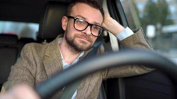 Satisfied bearded man driving a car down the street in sunny weather video