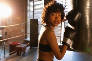 Women self defense girl power. African american woman fighter resting after fight training on boxing ring. Girl tired after punching boxing bag. Training day in gym, Strength fit body workout training photo