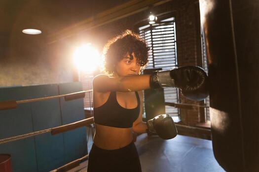 mujer yo defensa niña fuerza. africano americano mujer combatiente formación puñetazos en boxeo anillo. sano fuerte niña puñetazos boxeo bolsa. formación día en boxeo gimnasia. fuerza ajuste cuerpo rutina de ejercicio capacitación. foto