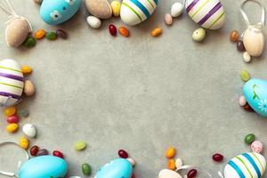 Happy Easter concept. Preparation for holiday. Easter eggs candy chocolate eggs and jellybean sweets on concrete stone grey background. Flat lay top view copy space banner. photo