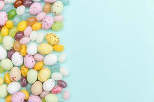 Happy Easter concept. Preparation for holiday. Easter candy chocolate eggs and jellybean sweets isolated on trendy pastel blue background. Simple minimalism flat lay top view copy space. photo