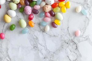 Happy Easter concept. Preparation for holiday. Easter candy chocolate eggs and jellybean sweets on trendy gray marble background. Simple minimalism flat lay top view copy space. photo