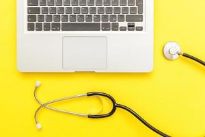 Stethoscope keyboard laptop computer isolated on yellow background. Modern medical Information technology and sofware advances concept. Computer and gadget diagnostics and repair photo