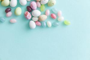 Happy Easter concept. Preparation for holiday. Easter candy chocolate eggs and jellybean sweets isolated on trendy pastel blue background. Simple minimalism flat lay top view copy space. photo