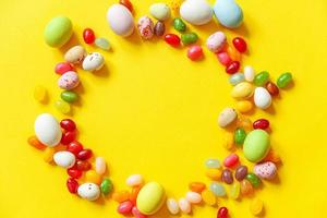 contento Pascua de Resurrección concepto. preparación para día festivo. Pascua de Resurrección caramelo chocolate huevos y frijol de jalea dulces aislado en de moda amarillo antecedentes. sencillo minimalismo plano laico parte superior ver Copiar espacio. foto