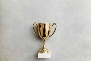 Simply flat lay design winner or champion gold trophy cup on concrete stone grey background. Victory first place of competition. Winning or success concept. Top view copy space. photo